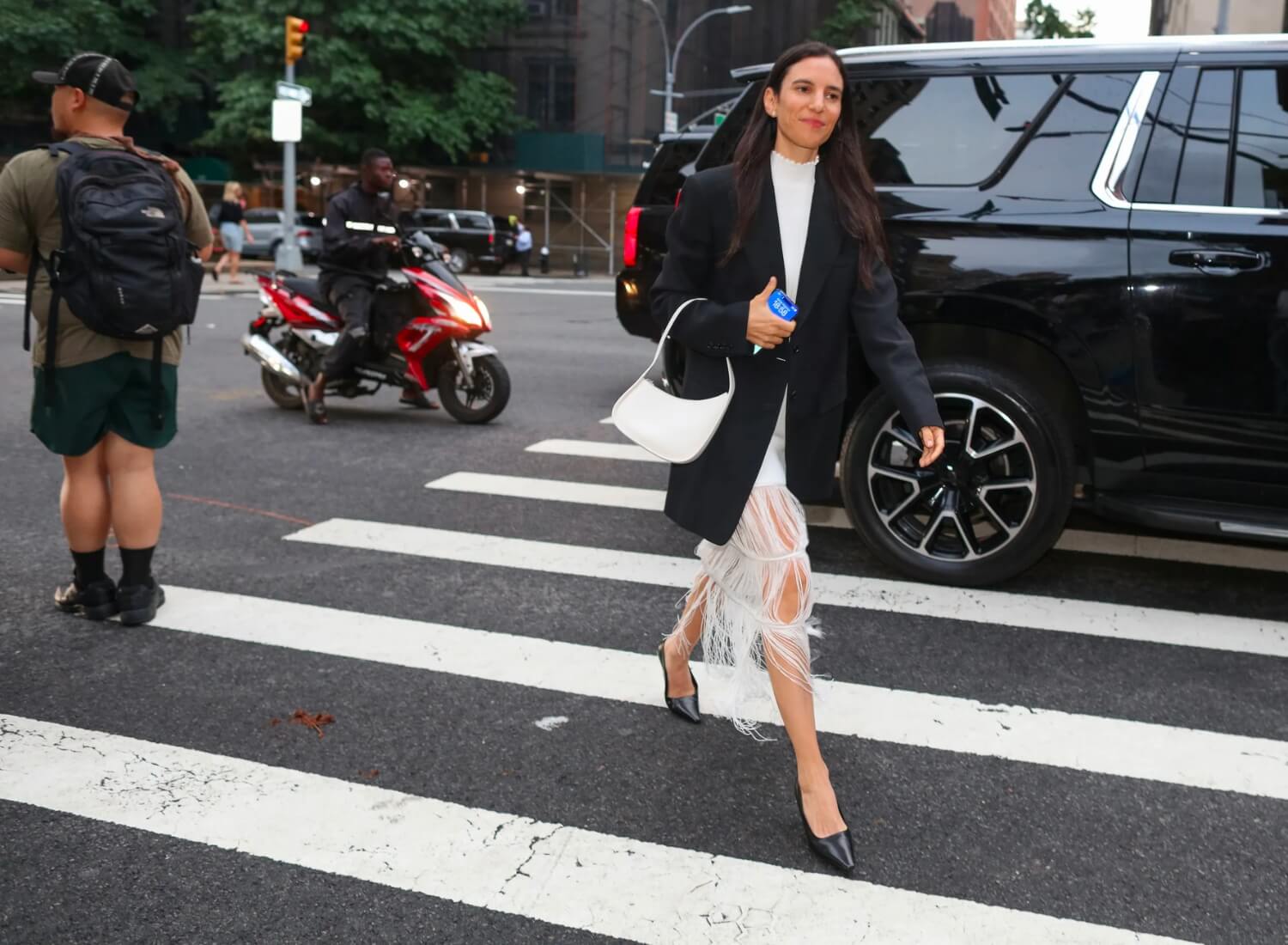 Woman wearing oversized black blazer with white fringed dress